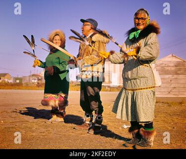 1960S KOTZEBUL ALASKA DREI ÄLTERE ESKIMOS IN TRADITIONELLER EINHEIMISCHER KLEIDUNG MANN, DER MIT GEFIEDERTEN RASSELN QILAUT-DRUM-FRAUEN SPIELT - KR23510 FRT001 HARS ÄLTERE FRAUEN LÄNDLICHE GESUNDHEIT KOPIEREN RAUM FREUNDSCHAFT GANZKÖRPERFRAUEN PERSONEN TRADITIONELLE INDIANER MÄNNER UNTERHALTUNG SENIOR MAN SENIOR ADULT NORDAMERIKA AUGENKONTAKT SENIOR FRAU NORTH AMERICAN PERFORMING ARTS ALASKA GLÜCK ALTER OLDSTERS OLDSTER STRATEGIE AUFREGUNG NIEDRIGEN WINKEL TRADITION STOLZ AUF DIE VERWENDUNG VON ÄLTESTEN INUIT KONZEPTUELLE RASSEL ETABLIERTEN INDIANISCHEN INUPIAT GEFIEDERTEN INDIANER ZWEISAMKEIT LUFTBILD INDIGENEN Stockfoto