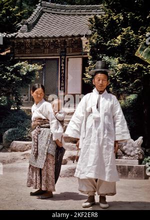 1950S FAMILIE TRADITIONELLE KLEIDUNG BABY IN SLING FRAU IN HANBOK VON CHIMA UND JEOGORI MANN IN BAJI HOSEN UND HUT PUSAN SÜDKOREA - KR9210 HAR001 HARS MÜTTER ALTE ZEIT NOSTALGIE ALTE MODE 1 JUGENDLICHE STIL JUNGE ERWACHSENE KLEINKIND HOSEN FAMILIEN LIFESTYLE GESCHICHTE FRAUEN VERHEIRATET EHEPARTNER EHEMÄNNER ZU HAUSE LEBEN KOPIEREN RAUM IN VOLLER LÄNGE DAMEN PERSONEN TRADITIONELLE MÄNNER VERTRAUEN PARTNER BLICKKONTAKT ORIENTALISCHE STILE UND TRADITION STOLZ TRÄGT KULTUR ETABLIERTE SLING STILVOLLE KOREA MODE JUGENDLICHE MITTLEREN ERWACHSENEN MITTLEREN ERWACHSENEN FRAU MÜTTER ZWEISAMKEIT FRAUEN JUNG ERWACHSENE FRAU HAR001 ALTMODISCH Stockfoto