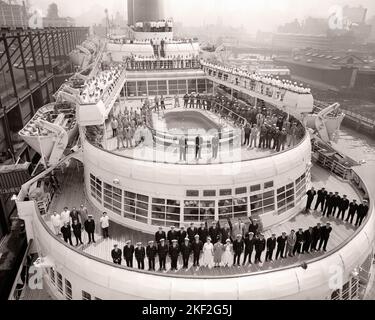 1950S UM 1954 STELLTE SICH DIE GESAMTE BESATZUNG DES SCHIFFES SS CONSTITUTION AUF DEM AFT DECK DES SCHIFFES ZUSAMMEN IN PORT NYC USA - S11966 RGE001 HARS KOPIEREN RAUM DAMEN PERSONEN INSPIRATION VEREINIGTE STAATEN VON AMERIKA MÄNNER BERUF SCHIFFE VERTRAUEN TRANSPORT B & W GESCHICK BERUF HAFEN FÄHIGKEITEN HIGH-ANGLE FREIZEIT KUNDENSERVICE KARRIERE AUSSEN ARBEIT STOLZ BESCHÄFTIGUNG NYC BERUFE KREUZFAHRT SCHIFF KONZEPTIONELLE NEW YORK STÄDTE STILVOLLE UNTERSTÜTZUNG NEW YORK CITY MITARBEITER OFFIZIERE AFT CIRCA ZUSAMMENARBEIT OCEAN LINER SS MITARBEITER DAMPFT 1954 SCHWARZ-WEISS-GESAMTE WERKTÄTIGEN ALTMODISCHEN GEFÄSS Stockfoto