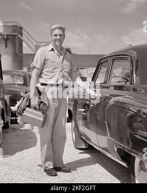 1950S LÄCHELNDER MANN MIT BLAUEM KRAGEN ARBEITER, DER DIE SMOKING-JACKE IN DER LUNCHBOX TRÄGT UND DIE HAND DER KAMERA AM GRIFF DER VIER TÜREN ANSCHAUT SEDAN AUTO - S279 HAR001 HARS GESUNDHEIT KOPIEREN RAUM IN VOLLER LÄNGE PERSONEN AUTOMOBIL PFLEGE MÄNNER BERUF VERTRAUEN TRANSPORT MITTLEREN ALTERS S & W AUGE KONTAKT FREIHEIT ERFOLG GESCHICKLICHKEIT TRÄUME BERUF GLÜCK FÄHIGKEITEN FRAU MITTLEREN ALTERS WELLNESS FRÖHLICHE STÄRKE AUTOS KARRIERE WAHL FORTSCHRITT ARBEIT STOLZ GELEGENHEIT BESCHÄFTIGUNG BERUFE LÄCHELT KONZEPTUELLE AUTOMOBILE FRÖHLICH STILVOLLE FAHRZEUGE INFRASTRUKTUR MITARBEITER ENTSPANNUNG SCHWARZ-WEISS KAUKASISCHE ETHNIE HAR001 ARBEITEN Stockfoto