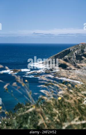 kantabrische See mit beeindruckenden Wellen, die mit großer Kraft gegen die großen Felsen der Klippen unter dem Leuchtturm, asturien, spanien, krachen Stockfoto