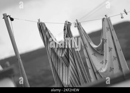 Schwarzweiß-Schwarz-Weiß-Bild von Kleidung an einer Wäscheleine in den walisischen Tälern. Geringe Schärfentiefe. Teleobjektiv 135mm Stockfoto
