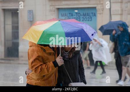 Valletta, Malta - 12. November 2022: Menschen, die an einem regnerischen Tag unter Sonnenschirmen spazieren Stockfoto