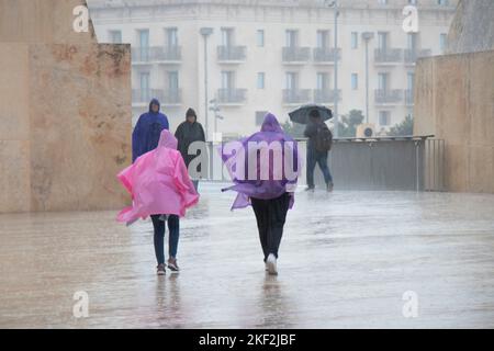 Valletta, Malta - 12. November 2022: Menschen, die Regenponchos und Regenschirme tragen, wandern an einem regnerischen Tag Stockfoto