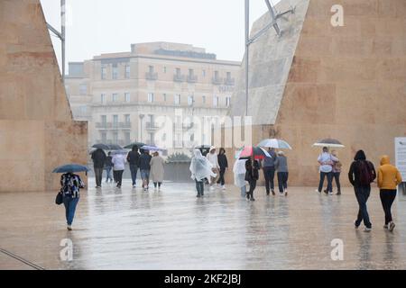 Valletta, Malta - 12. November 2022: Menschen, die Regenponchos tragen und Regenschirme halten, laufen an einem regnerischen Tag Stockfoto