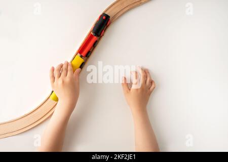High-Angle-Aufnahme einer Kinder Hände spielen mit Holzspielzeug Zug auf weißem Hintergrund mit leerem Raum für Text mit Draufsicht. Stockfoto