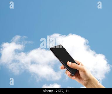 Männliche Hand präsentiert eine Smartphone-Bildschirm-Anwendung über isolierten Cloud-Hintergrund.Online-Cloud-Kommunikationskonzept Stockfoto