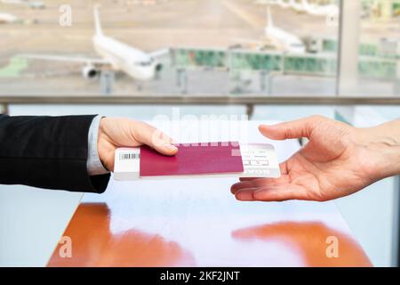 Zugeschnittene Aufnahme einer nicht erkennbaren Stewardess, die am Flugsteig des Flughafens ein Ausweisbuch an den Passagier zurückgibt Stockfoto