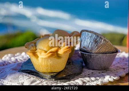 Portugiesische Gerichte, ofengebackene Hähnchenkuchen empada de Frango, serviert im Freien mit Blick auf den blauen, sonnigen Atlantik in der Nähe von Sintra im Raum Lissabon, Portugal Stockfoto