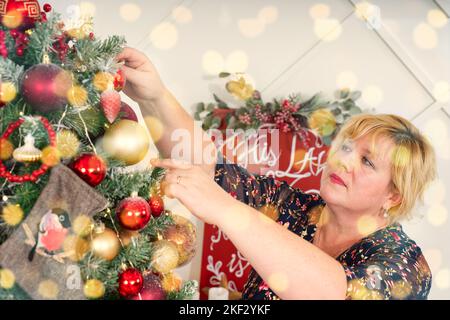Frau Dekoration schönen Weihnachtsbaum zu Hause, Nahaufnahme. weihnachtsferien und Menschen Konzept. Stockfoto