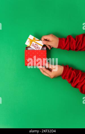 Weibliche Hände nehmen einen Geschenkgutschein aus einer Geschenkbox, ein modernes Geschenk für Online-Dienste und Shopping. Draufsicht, flach liegend Stockfoto