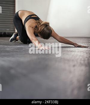 Eine junge Frau macht Dehnübungen im Fitnessstudio. Stockfoto