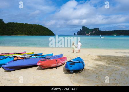 Koh Ph Phi Thailand, ein paar Männer und Frauen, die am Strand in der Morgensonne mit türkisfarbenem Meer spazieren Stockfoto