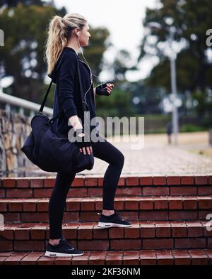 Es ist Zeit, ins Fitnessstudio zu gehen. Eine sportliche junge Frau, die eine Sporttasche trägt. Stockfoto