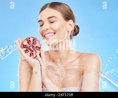 Schönheit, Wasser und Granatapfel mit einer Model-Frau im Studio auf blauem Hintergrund für Ernährung oder Flüssigkeitszufuhr. Essen, Reinigung und Pflege mit einem Stockfoto