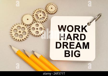 Geschäfts- und Finanzkonzept. Auf dem Tisch sind Zahnräder, Bleistifte und ein Notizbuch mit der Aufschrift - Work Hard Dream Big Stockfoto