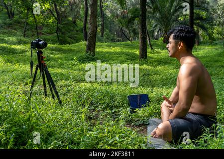 Ein hispanischer Mann, der einen virtuellen Fitnesskurs auf einer Videokonferenz in einem Wald durchführt Stockfoto