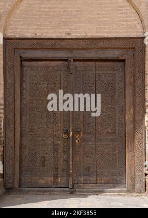 Nahaufnahme der schönen traditionellen Holztür von Madrasa mit floralen und geometrischen Schnitzereien, Hisor oder Hissar, Tadschikistan Stockfoto