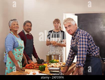Die Küche ist ein Treffpunkt für Freunde. Eine Gruppe von Menschen, die in der Küche kochen. Stockfoto