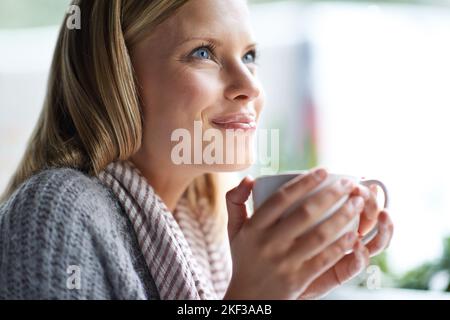 Wir alle brauchen einen Ort, um alleine zu sein. Eine junge Frau, die in einem Café sitzt. Stockfoto