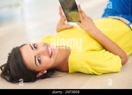 Mal sehen, was online passiert. Eine junge Frau, die zu Hause ein digitales Tablet nutzt. Stockfoto