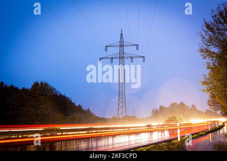 Langenhagen, Deutschland. 16.. November 2022. Am frühen Morgen fahren Fahrzeuge an einem Strompylon in der Region Hannover vorbei. Im vergangenen Jahr lag die durchschnittliche Nichtverfügbarkeit von Strom in Deutschland bei 12,7 Minuten pro Endverbraucher - so die Bundesnetzagentur, die Berichte von 850 Netzbetreibern erhält. (Aufnahme mit langer Belichtungszeit) Quelle: Moritz Frankenberg/dpa/Alamy Live News Stockfoto