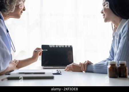 Eine leitende Ärztin konsultiert ihre Patientin in der Klinik auf einem Laptop. Medizinkonzept Stockfoto