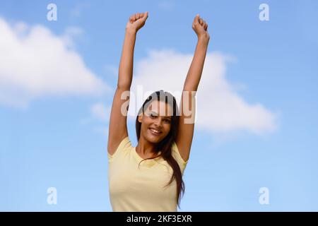 Freiheit, Energie und Frau in der Natur gegen einen blauen Himmel, um sich mit Frieden, Glück und Lächeln zu entspannen. Aufgeregt, frei und indisch Mädchen in ihrer Jugend glücklich mit Stockfoto