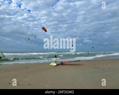 Surfer und Kite Surfer an einem windigen und sonnigen Tag am Nordseestrand Stockfoto