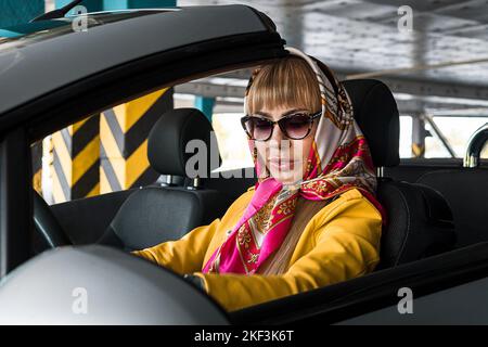Junge Frau, die in den Rückspiegel des Autos schaut Stockfoto