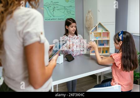 Schüler zeigen Glühbirne und LED-Lampe in Ökologie Klassenzimmer Stockfoto