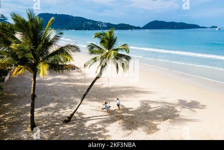 Paar Männer und Frauen beobachten den Sonnenuntergang am Strand, Patong Beach während des Sonnenuntergangs in Phuket Thailand und Palmen während des Sonnenuntergangs am Strand. Stockfoto