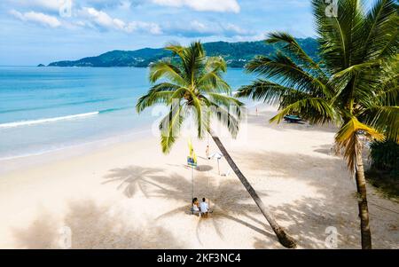 Paar Männer und Frauen beobachten den Sonnenuntergang am Strand, Patong Beach während des Sonnenuntergangs in Phuket Thailand und Palmen während des Sonnenuntergangs am Strand. Stockfoto