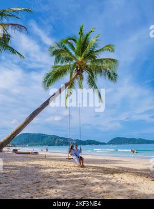 Paar Männer und Frauen beobachten den Sonnenuntergang am Strand, Patong Beach während des Sonnenuntergangs in Phuket Thailand und Palmen während des Sonnenuntergangs am Strand. Stockfoto