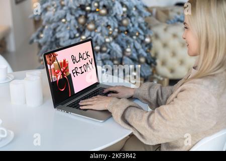 Black Friday Shopping-Konzept auf dem schwarzen Bildschirm des Laptops vor verschwommenem weihnachtslicht Hintergrund geschrieben Stockfoto