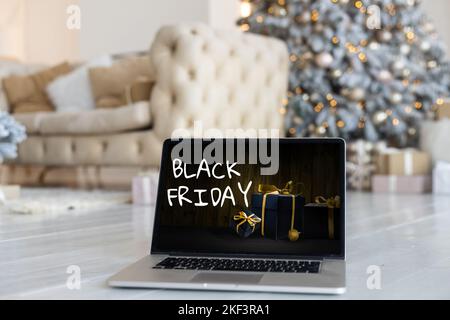 Black Friday Shopping-Konzept auf dem schwarzen Bildschirm des Laptops vor verschwommenem weihnachtslicht Hintergrund geschrieben Stockfoto