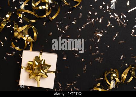 Geschenk- oder Geschenkbox und goldenes Konfetti auf schwarzem Tisch Draufsicht. Flat Lay Komposition mit Copyspace für weihnachten, Neujahr , Geburtstag, Muttertag, schwarzer freitag , Verkauf, Aktionen, Weihnachten oder Hochzeit. Stockfoto
