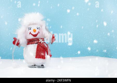 Netter glücklicher Schneemann mit flauschiger Mütze und rotem Schal, der im Schnee steht. Cartoon, lustig. Weihnachten, Neujahr Hintergrund mit Winter und Schneefall. Cop Stockfoto