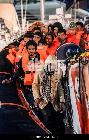 Roccella Jonica, Italien. 16.. November 2022. Migranten werden bei der Ankunft in Roccella Jonica beim Aussteigen aus dem Patrouillenboot gesehen. 28 Migranten, hauptsächlich aus Bangladesch, wurden auf einem Schiff in Not fast 115 Seemeilen vor der Küste gerettet und von der italienischen Küstenwache in die südliche Stadt Roccella Jonica (Italien) gebracht. Mitglieder des Roten Kreuzes und Ärzte ohne Grenzen leistten Migranten nach ihrer langen Reise aus Libyen lokale Hilfe. Kredit: SOPA Images Limited/Alamy Live Nachrichten Stockfoto