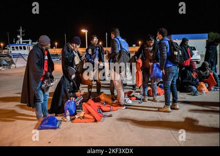 Roccella Jonica, Italien. 16.. November 2022. Nach der Landung in Roccella Jonica sprechen Migranten mit Mitgliedern des UNHCR. 28 Migranten, hauptsächlich aus Bangladesch, wurden auf einem Schiff in Not fast 115 Seemeilen vor der Küste gerettet und von der italienischen Küstenwache in die südliche Stadt Roccella Jonica (Italien) gebracht. Mitglieder des Roten Kreuzes und Ärzte ohne Grenzen leistten Migranten nach ihrer langen Reise aus Libyen lokale Hilfe. Kredit: SOPA Images Limited/Alamy Live Nachrichten Stockfoto