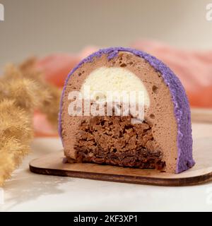 Mini-Mousse-Kuchen mit Schokolade Velours bedeckt. Beutel Form modernen europäischen Dessert mit Creme Blätterteig innen. Restaurant, Backmenü oder Rezeptkonzept. C Stockfoto