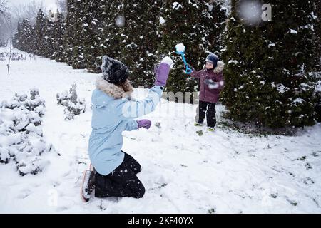 Glückliche Familie, Mutter und Sohn Spaß im Freien im Winter verschneiten Natur Hintergrund. Mama und Kind spielen Schneeball im Winterpark im Freien Stockfoto