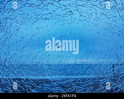 Zerbrochenes Glas mit Rissen. Abstrakt geknackt Schuss Fenster auf blau Stockfoto