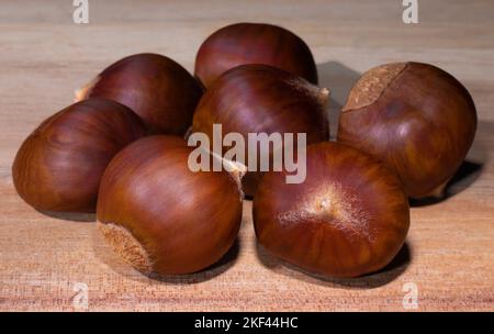 Gruppe von Kastanien frisch vom Baum auf einem Holztisch Stockfoto