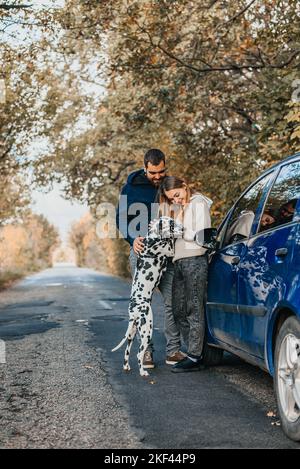 Glückliches Paar, das mit einem Hund im Park spielt. Stockfoto