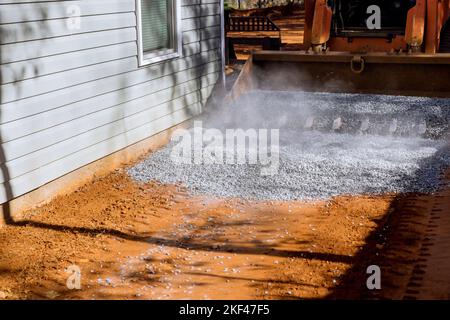 Im Rahmen der Reparaturarbeiten auf der Baustelle wurde der Lader-Bagger zum Entladen von Schotter verwendet Stockfoto