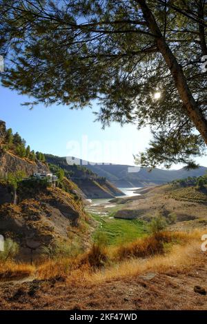 Die Trockenheit im Sommer zeigt ein trockenes Bett und einen extrem niedrigen Wasserstand in Iznajar Embalse, dem größten Stausee in Andalusien, Spanien Stockfoto