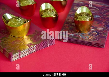 Chinesische Neujahrspakete mit chinesischen Goldbarren auf rotem Hintergrund. Chinesisches Neujahrs-Dekorationskonzept. Stockfoto