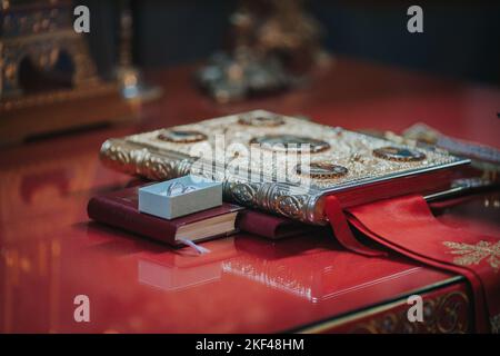 Die Bibel mit schönen Mustern, die auf dem Tisch liegen, mit heiligen Büchern und den Ringen, die für eine Hochzeitszeremonie bereit sind Stockfoto