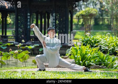 Asiatische Mann Training mit Tai Chi am Morgen im Park, chinesische Kampfkunst, gesunde Pflege für ein gesundes Leben Konzept. Stockfoto